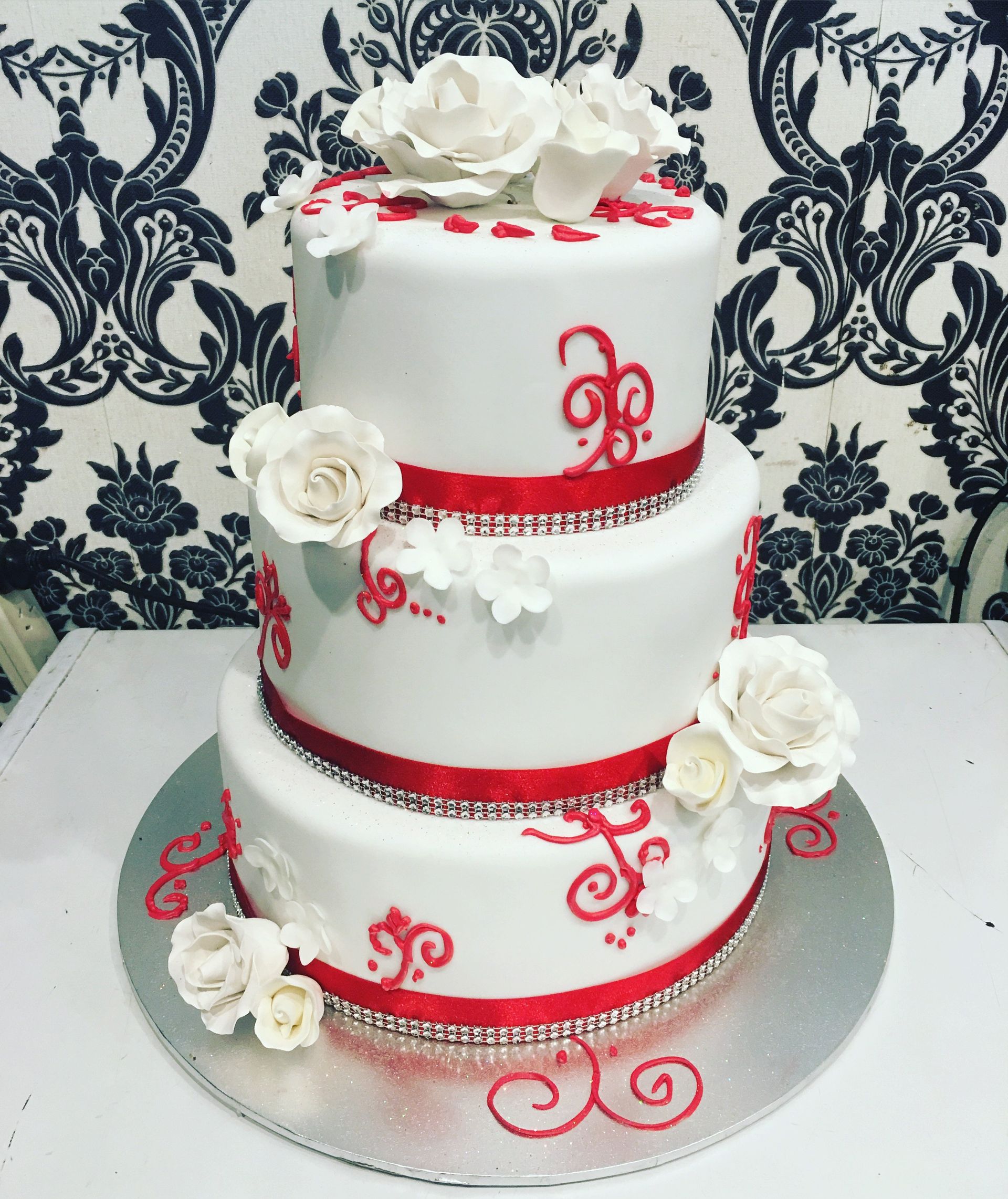 white triple layer cake with red accents and white flowers