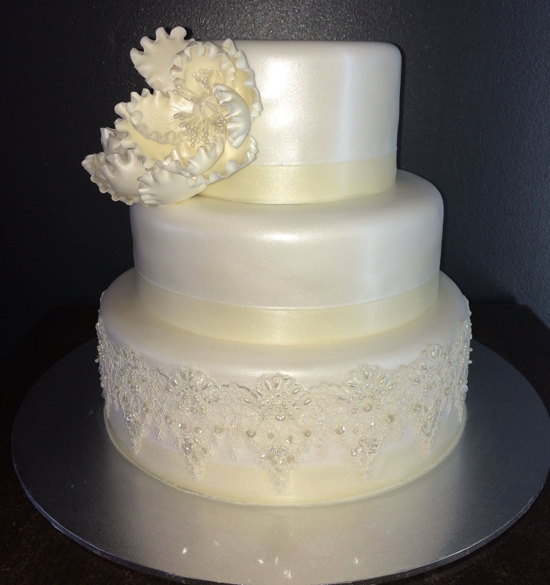white triple layer cake with rose accents and bride and groom on top