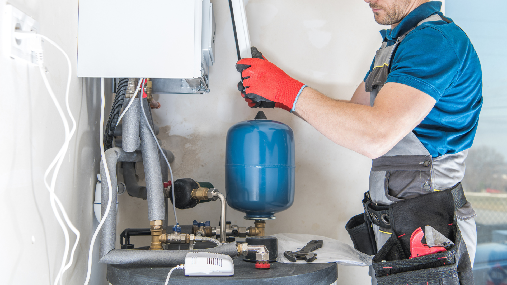 A man is working on a water heater in a room.