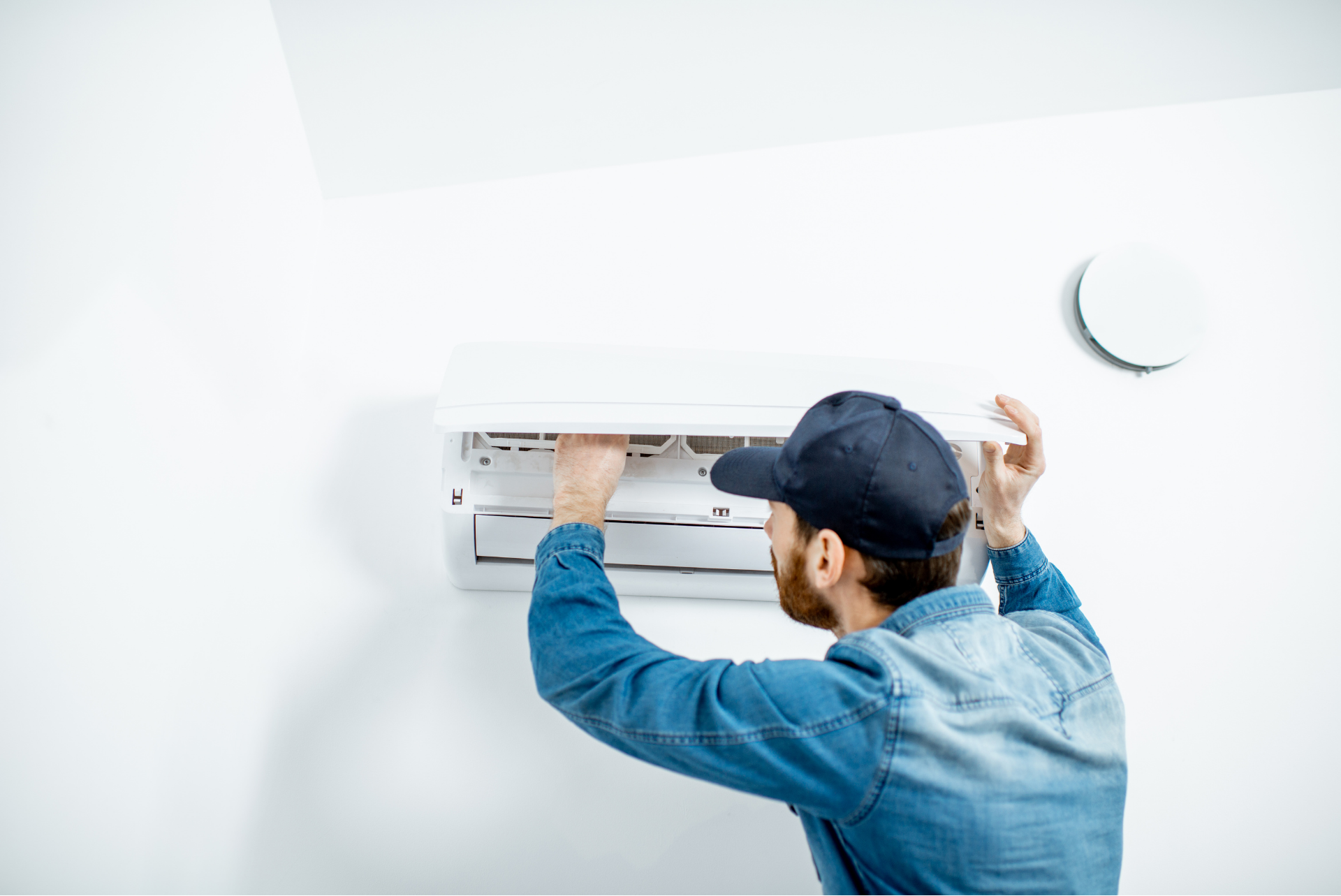 A man is installing an air conditioner on a wall.