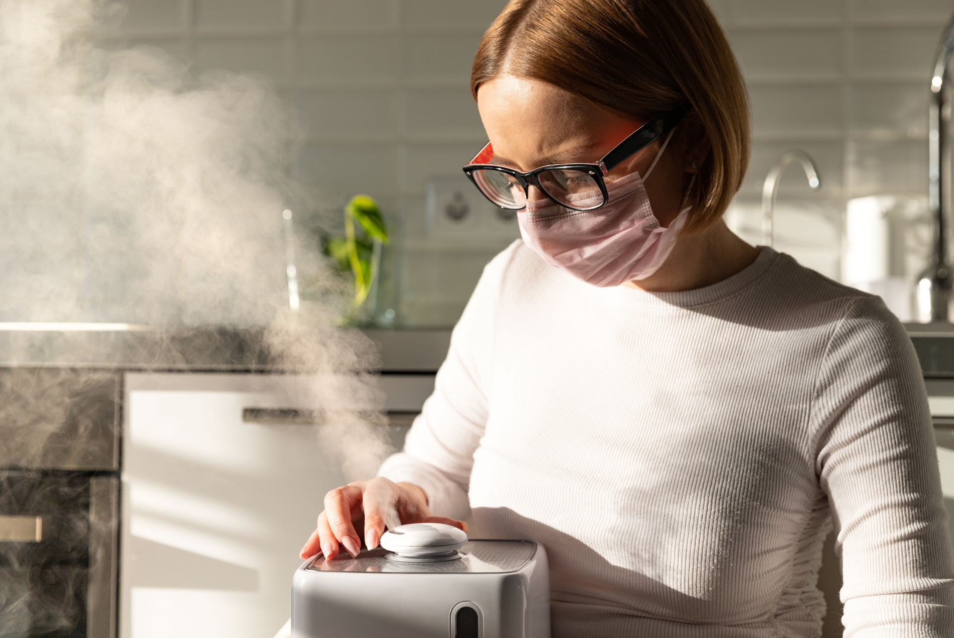 A woman wearing a mask and glasses is using an ultrasonic humidifier.