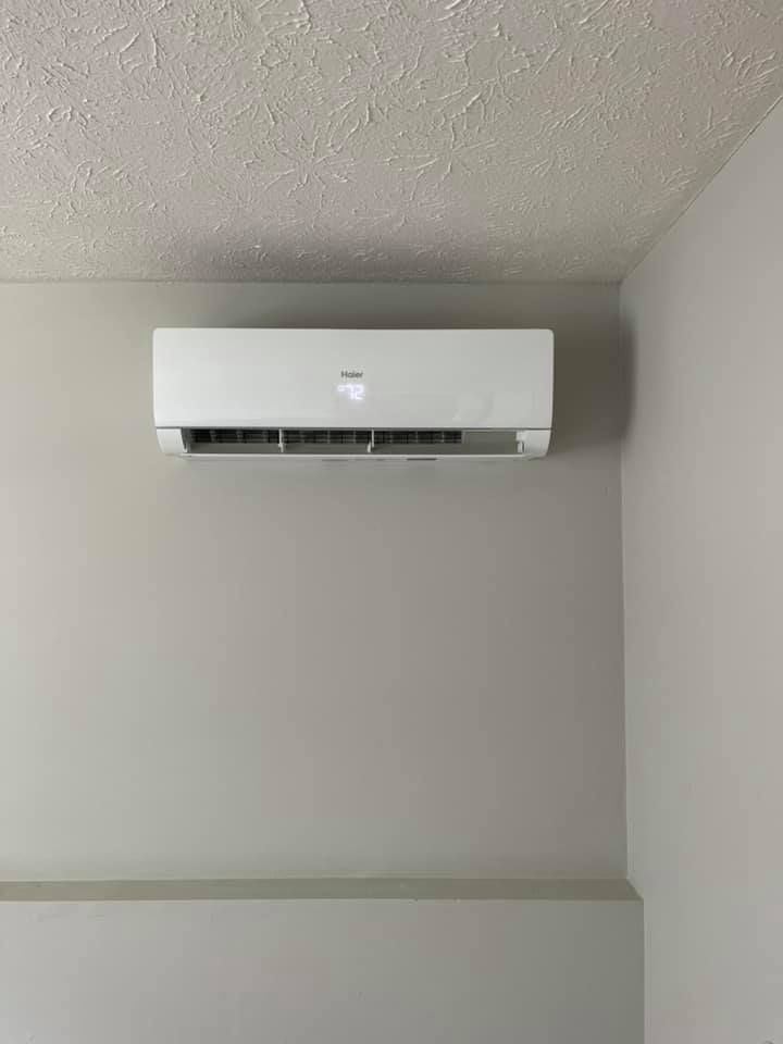 A white air conditioner is hanging on a wall in a room.
