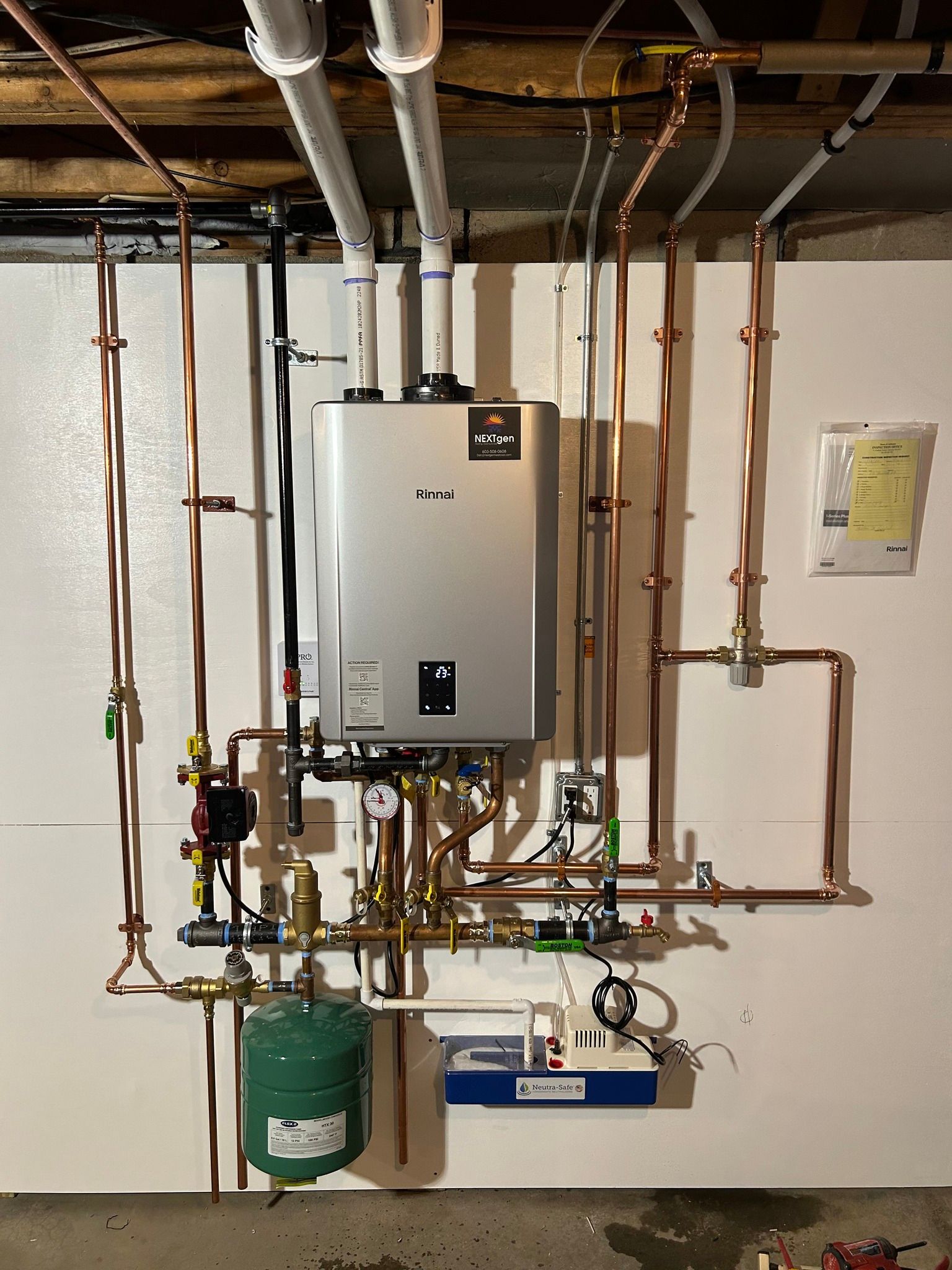 A water heater is hanging on a wall next to copper pipes.