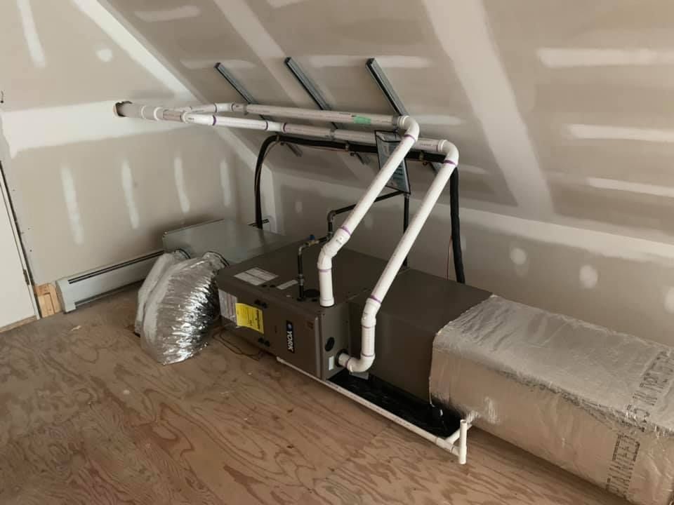 A room with a ceiling fan and pipes hanging from it.