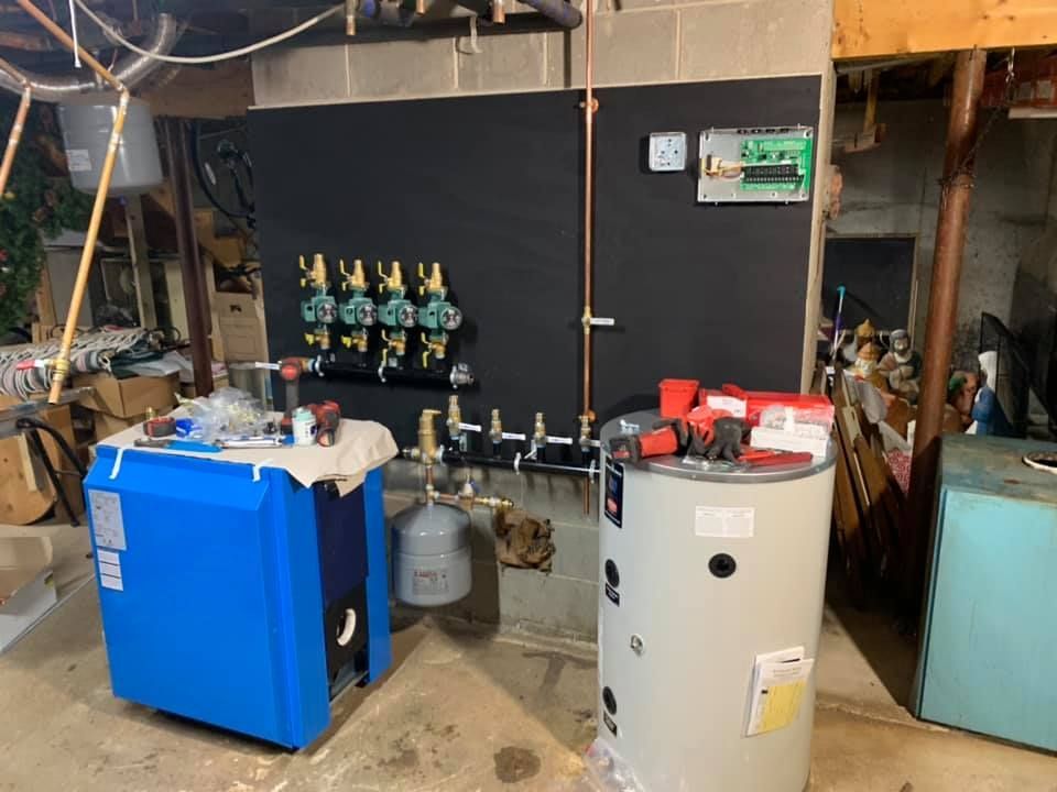 A blue boiler and a white water heater are in a basement.