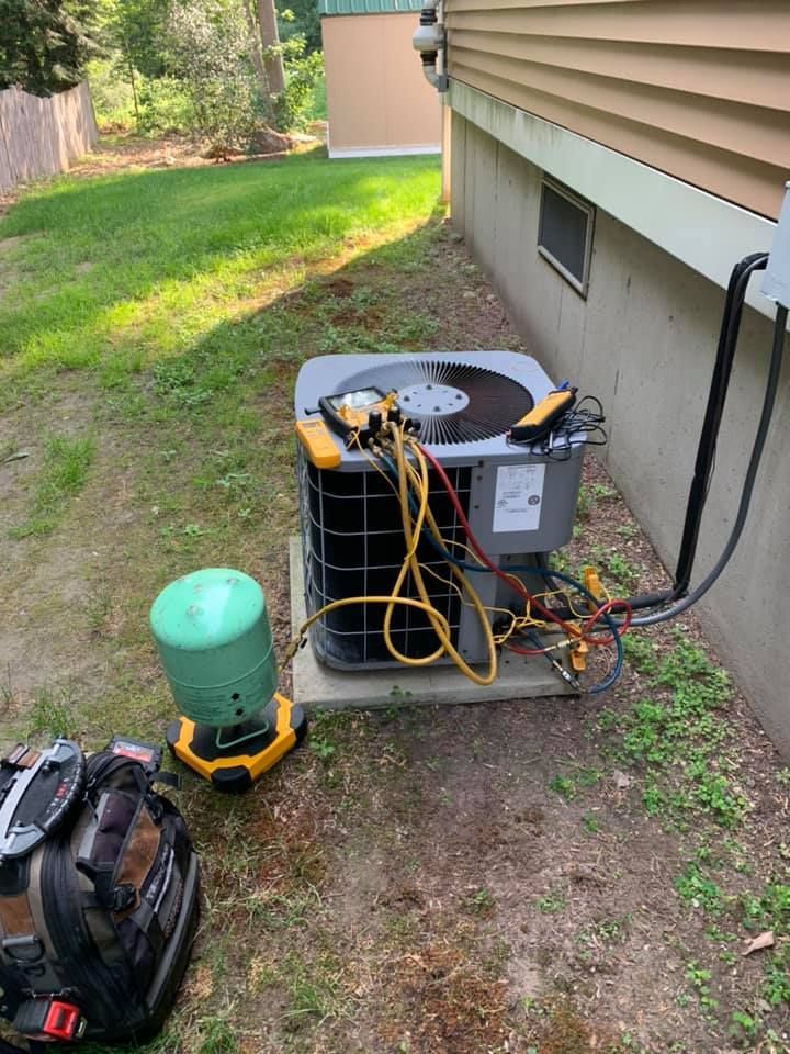An air conditioner is being installed in the backyard of a house.