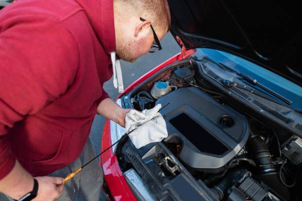 A man is looking under the hood of a car.