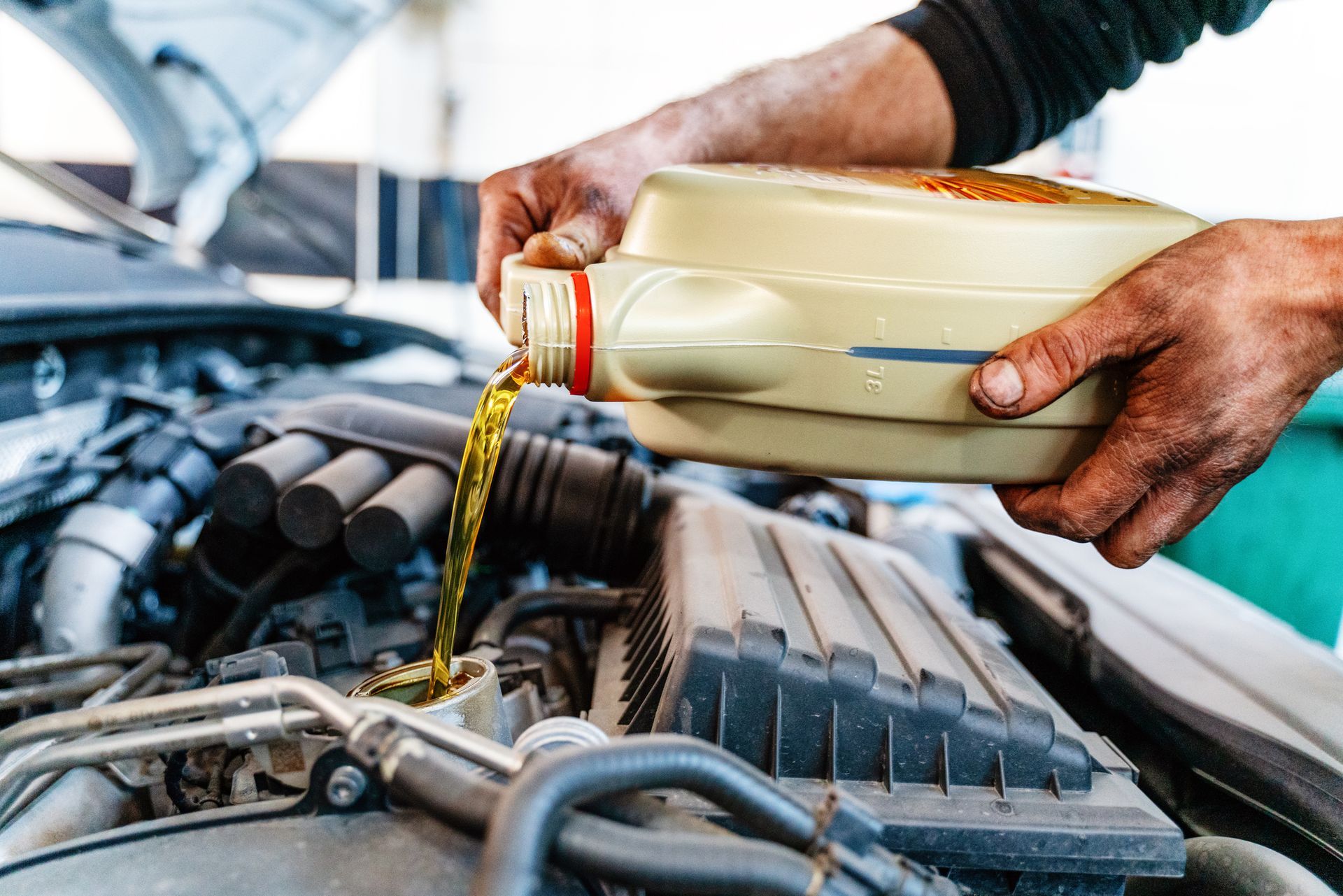 A man is pouring oil into a car engine.