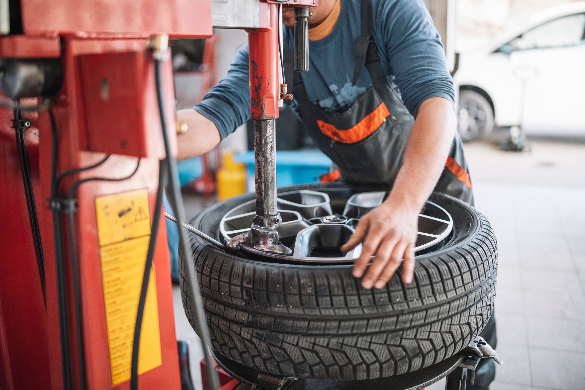A man is changing a tire on a machine in a garage.