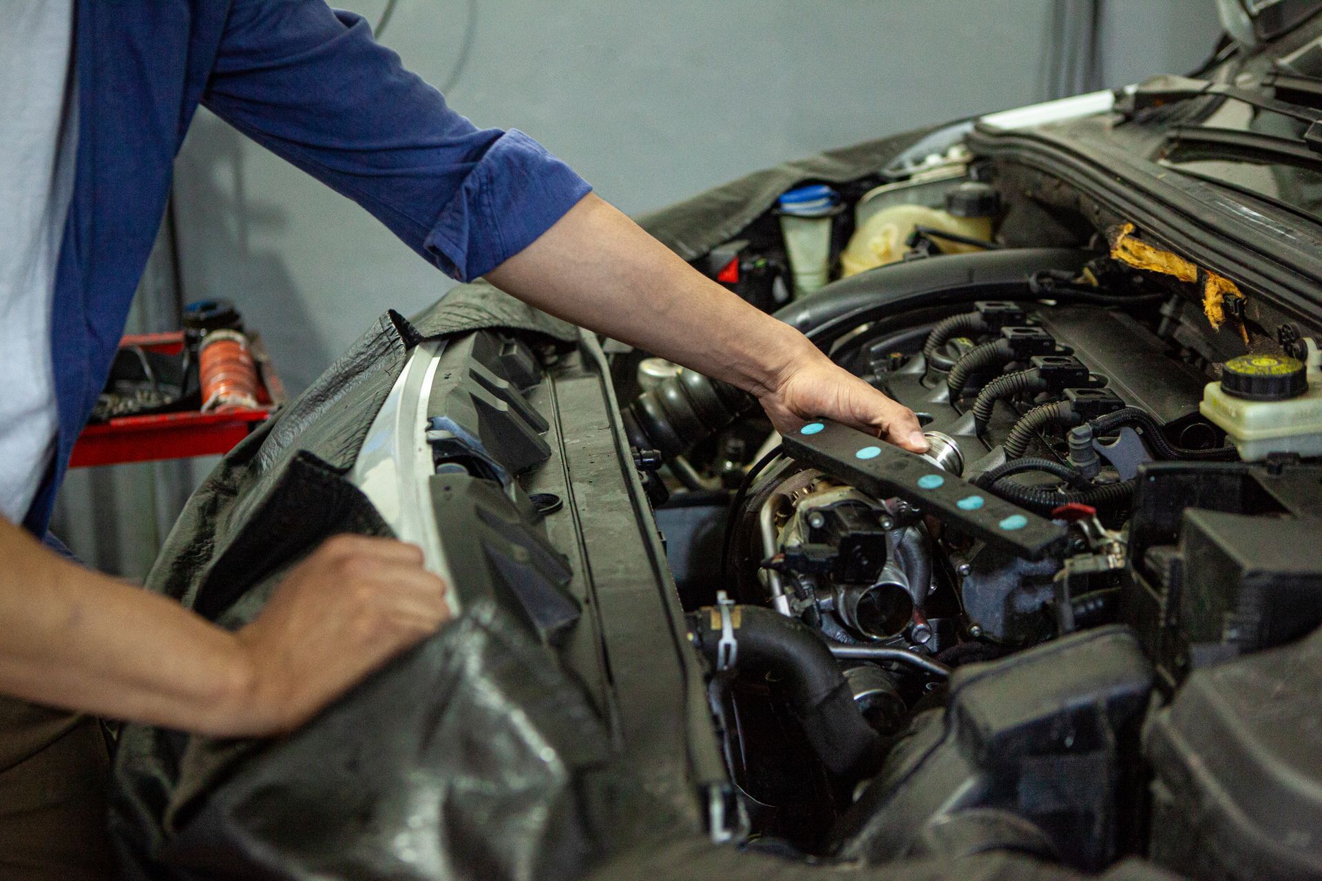 A man is working on the engine of a car in a garage.