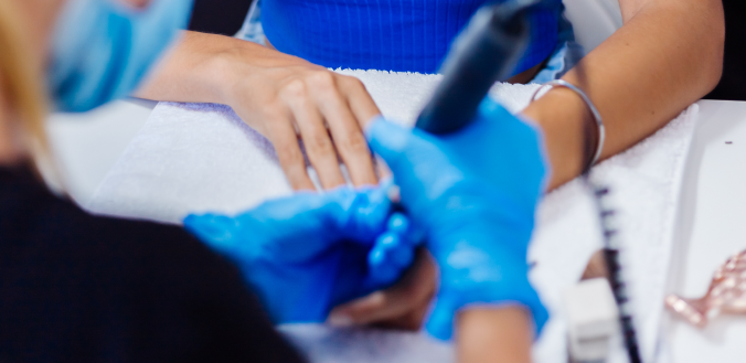 Uma mulher está pintando as unhas com uma manicure em um salão.