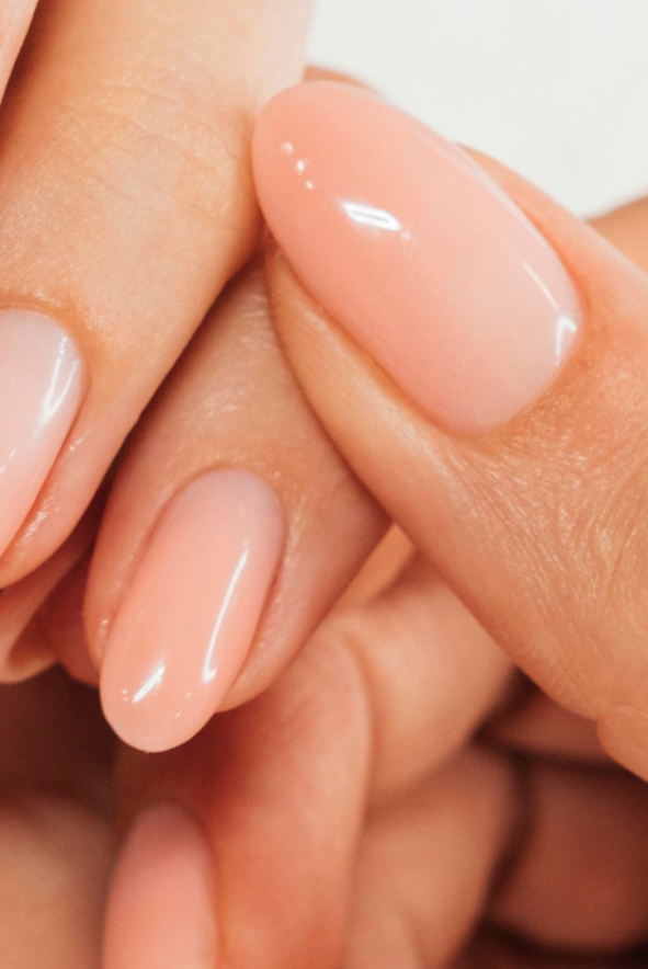 Um close das unhas de uma mulher com esmalte rosa