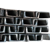 Pila de vigas de acero en forma de U, metal gris sobre un fondo blanco.