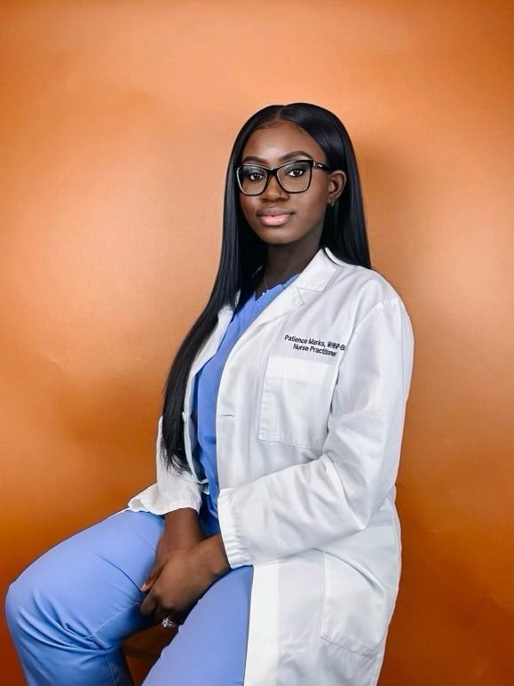 A woman in a lab coat and scrubs is sitting on a chair.