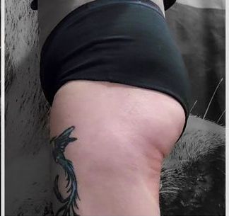 A woman with a tattoo on her leg is wearing black underwear.