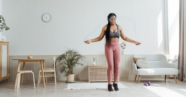 A woman is jumping a jump rope in a living room.