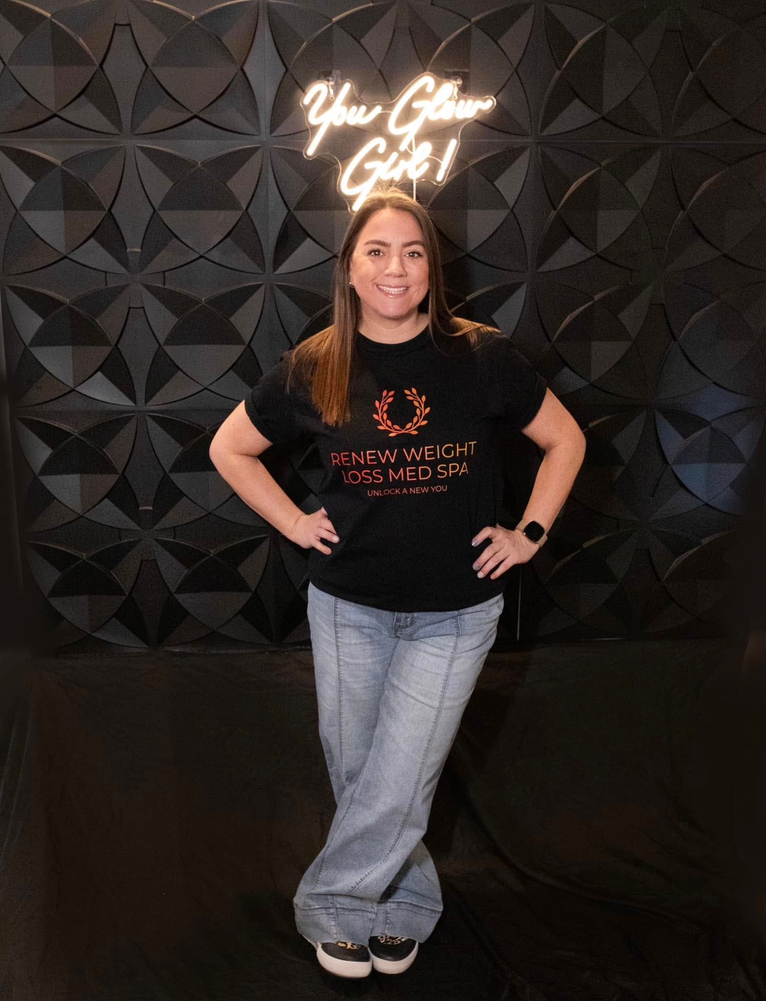 A woman is standing in front of a neon sign that says `` you glow girl ''.