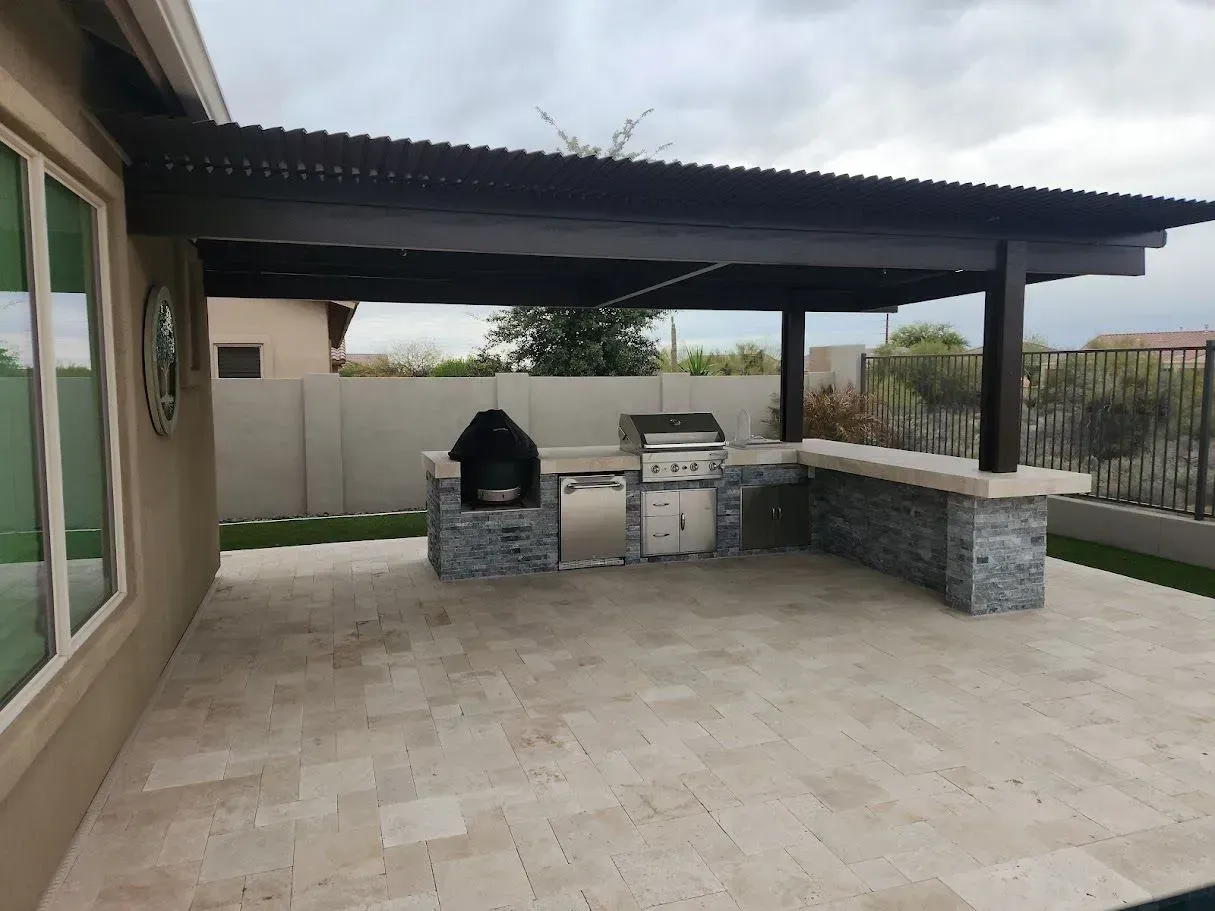 A large outdoor kitchen with a grill under a pergola