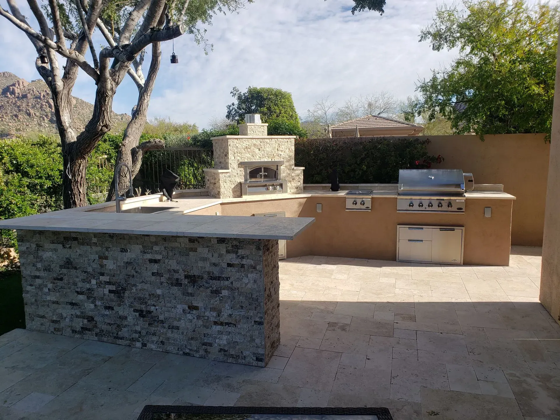 An outdoor kitchen with a grill and a fireplace