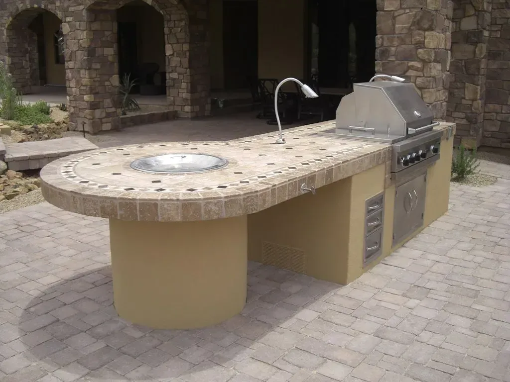 A large outdoor kitchen with a grill and sink