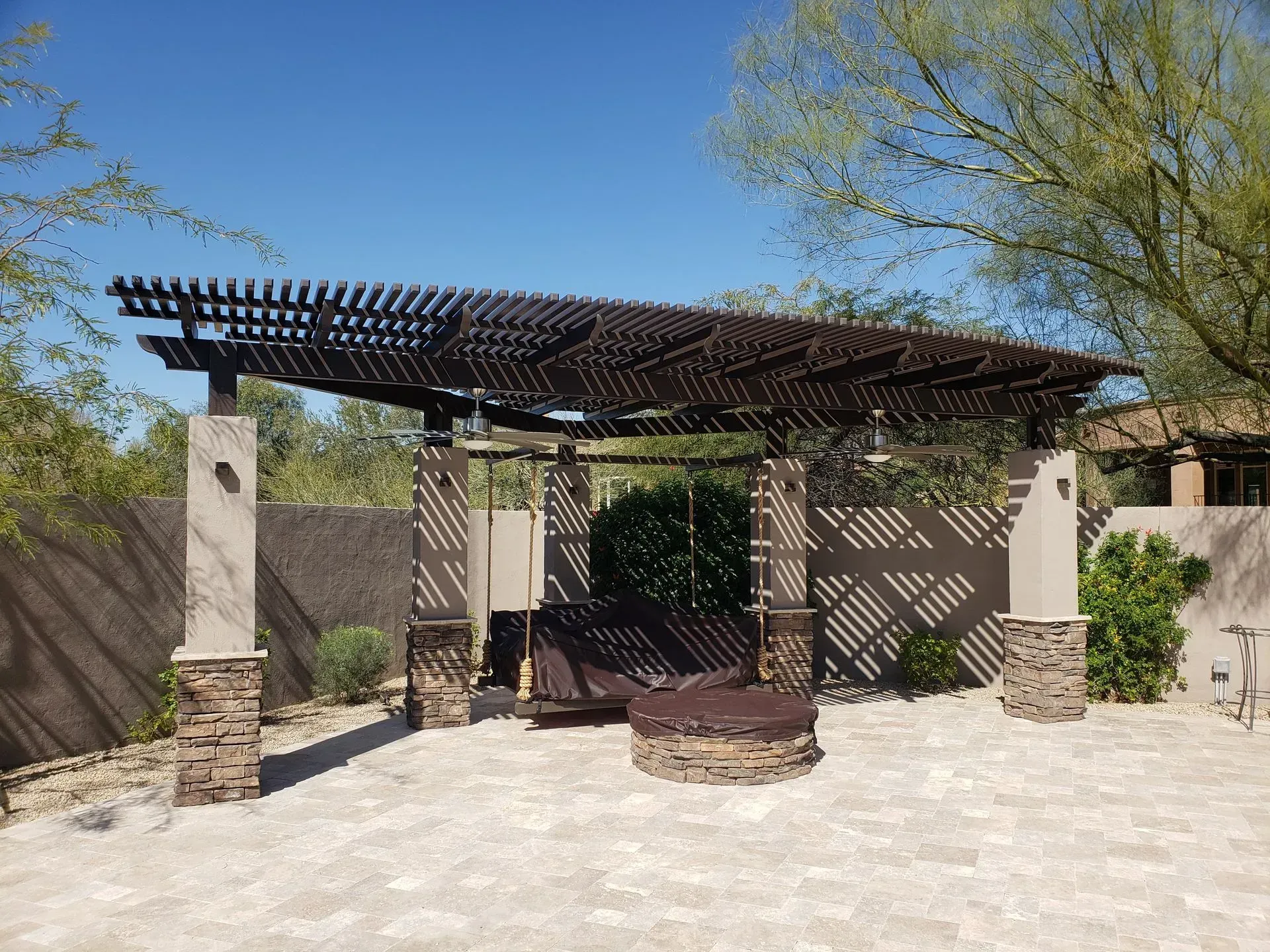 A wooden pergola with a fireplace underneath it