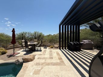 A fire pit in the middle of a patio next to a pool at night.