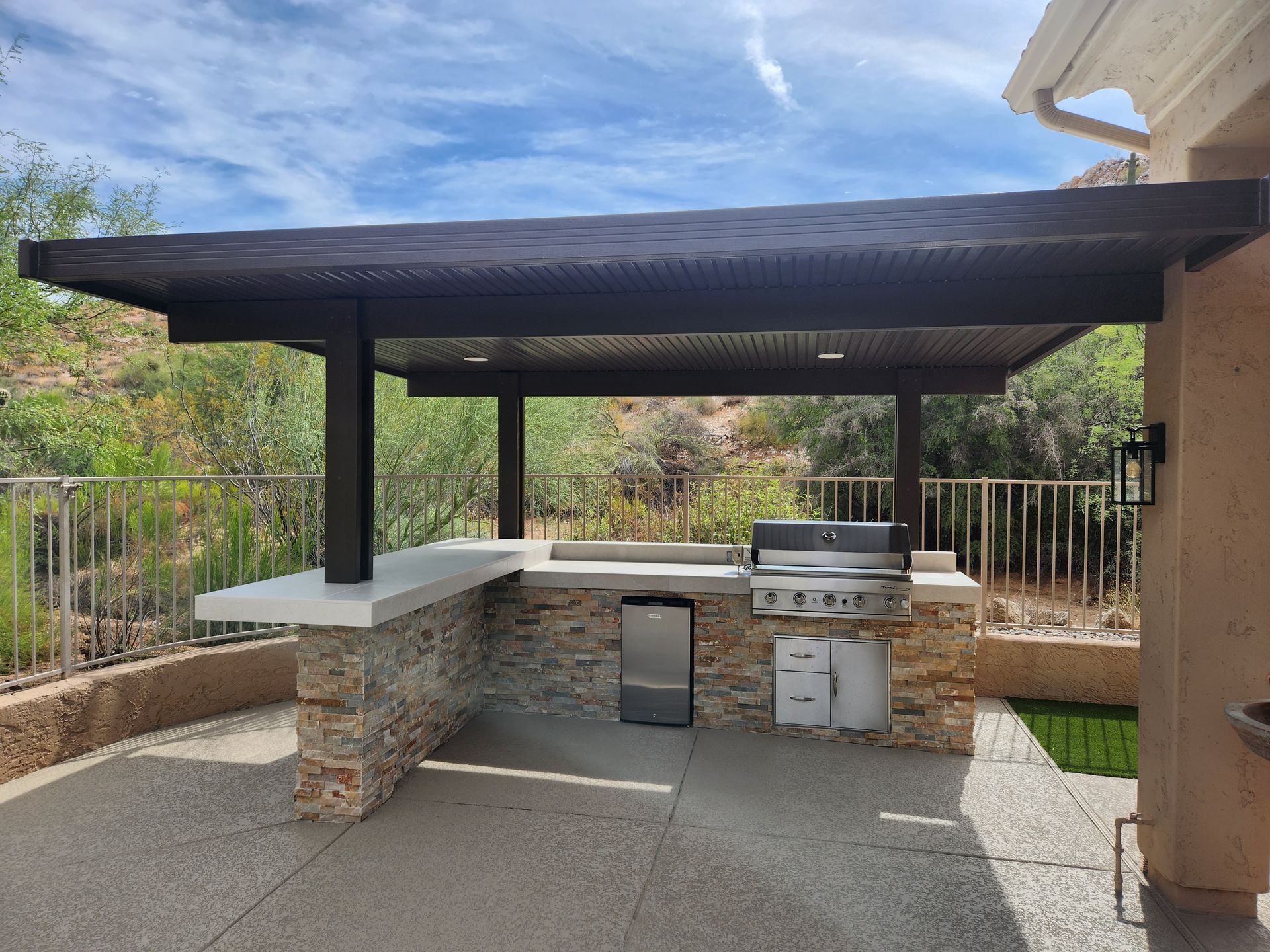 A large outdoor kitchen with a covered area and a grill.