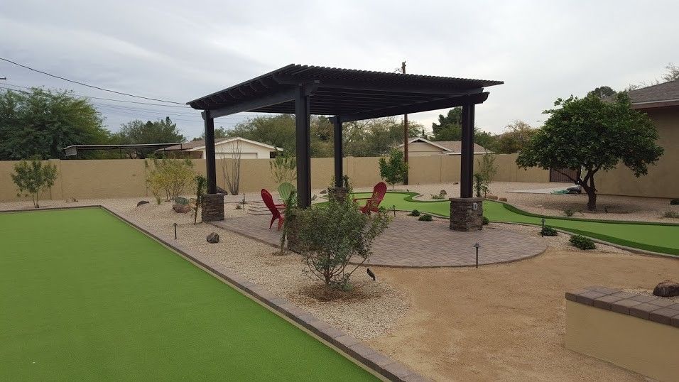 A backyard with a pergola and a green lawn