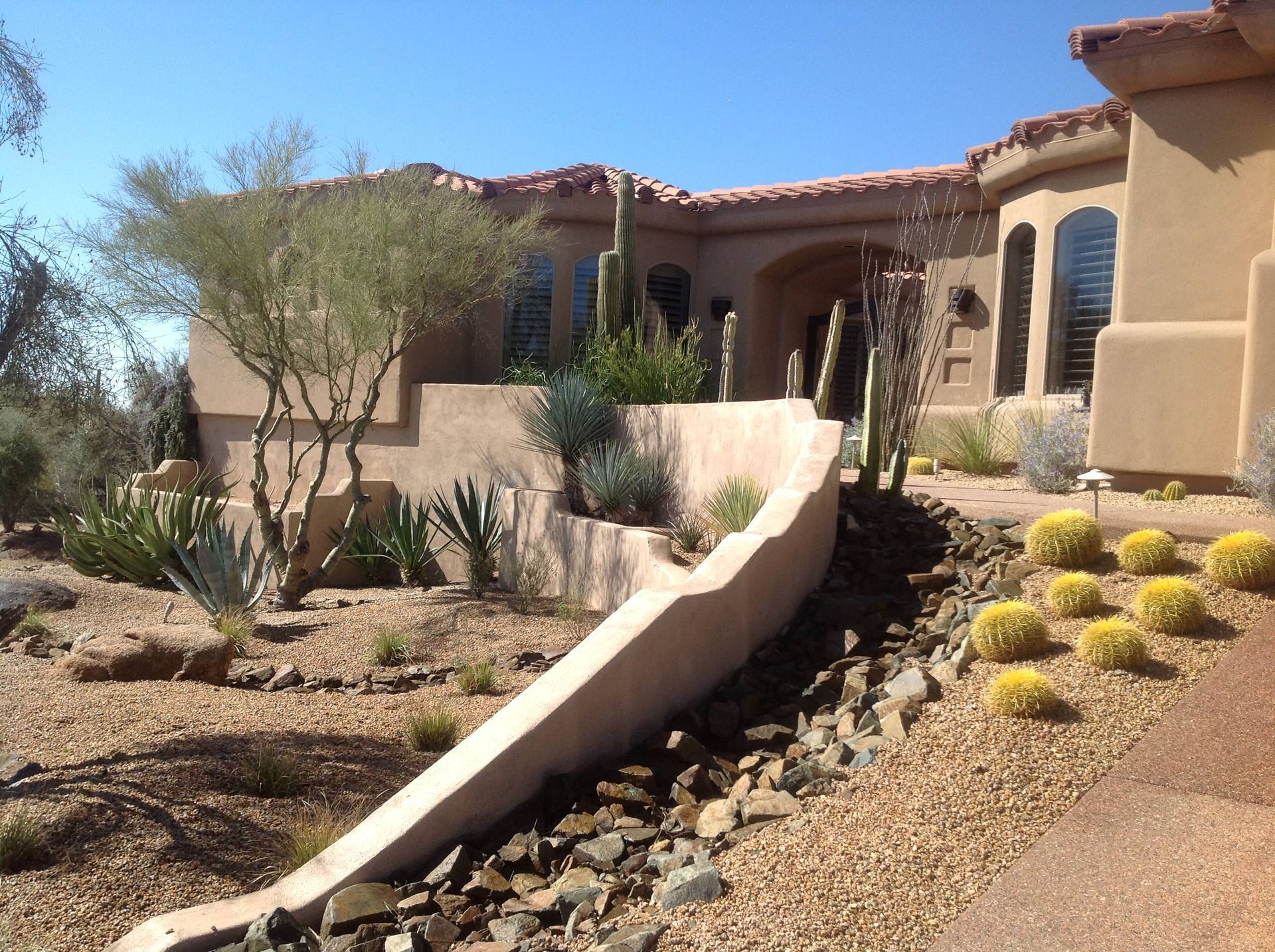 A large house is surrounded by rocks and plants