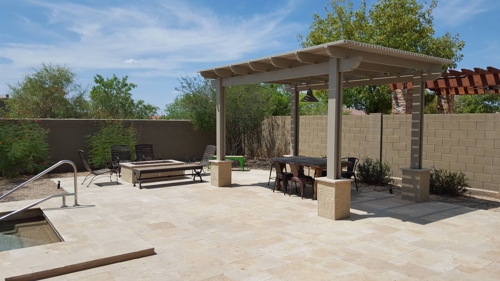 A patio with a pergola and a pool in the background