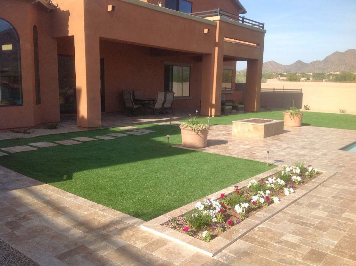 A large house with a lush green lawn and flowers in front of it.