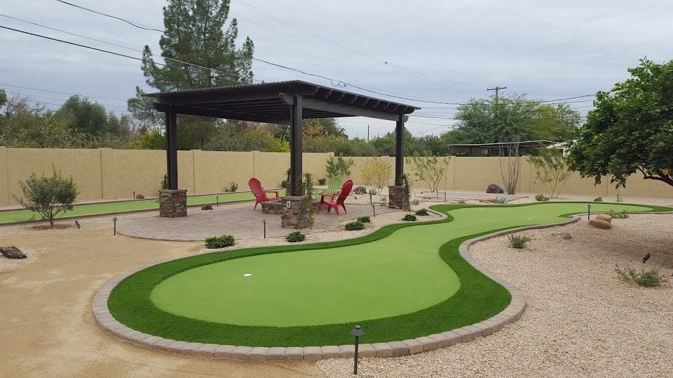 A backyard with a putting green and a pergola.