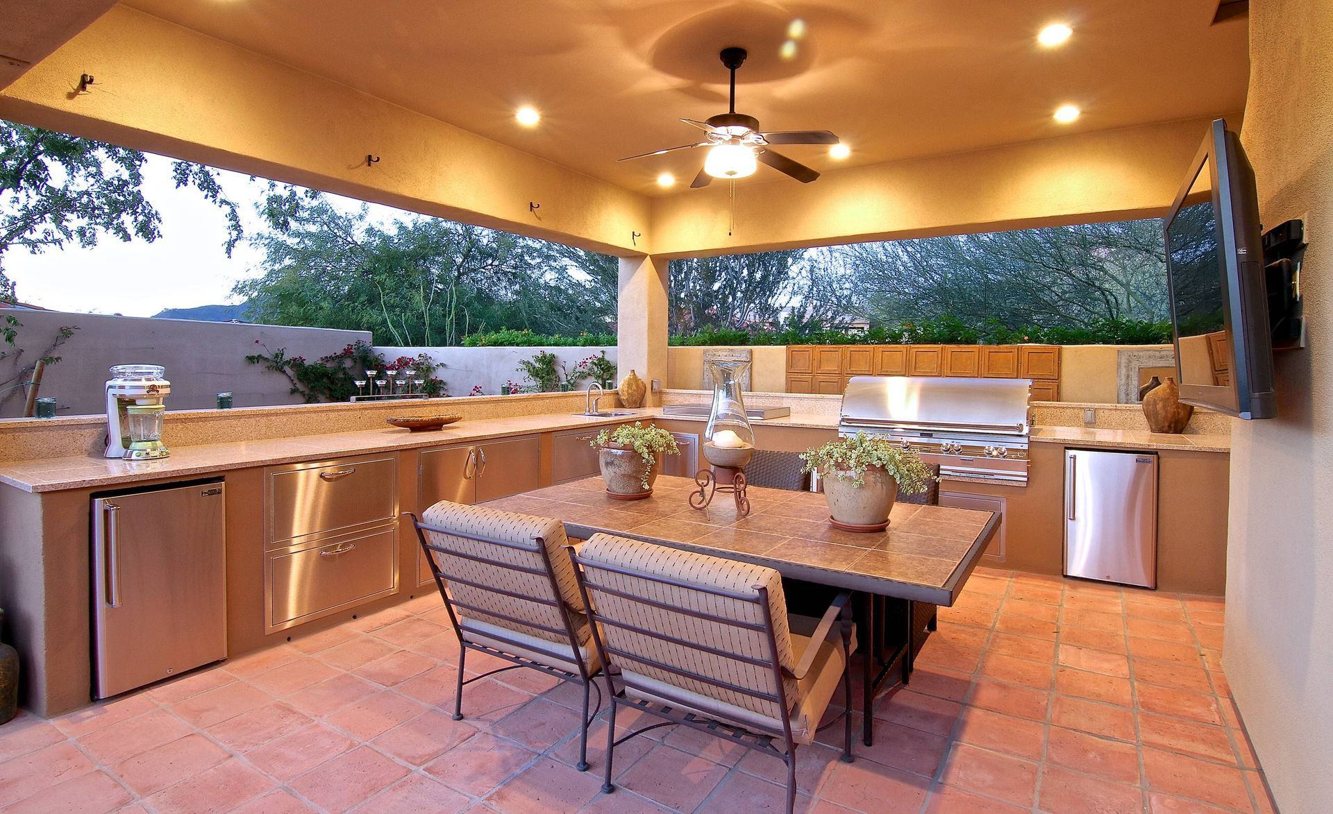 An outdoor kitchen with a table and chairs and a ceiling fan