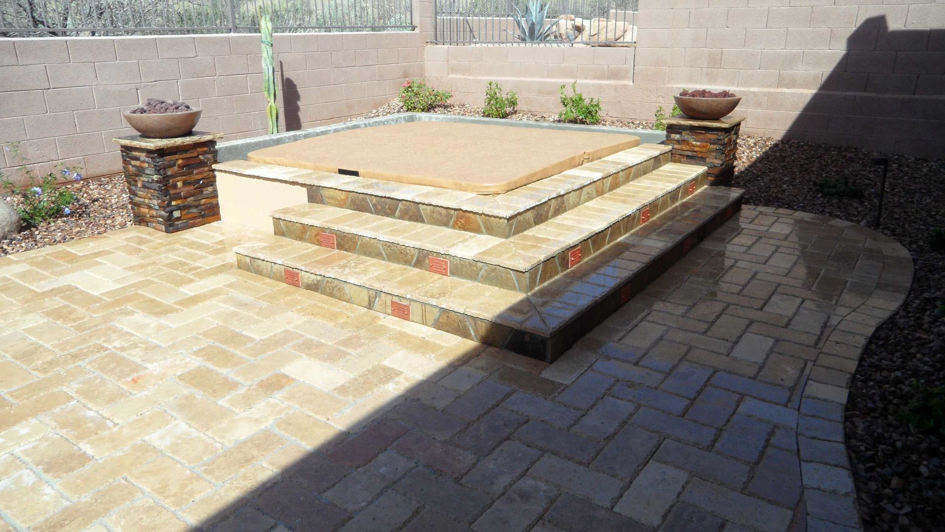 A brick patio with steps leading up to a hot tub.