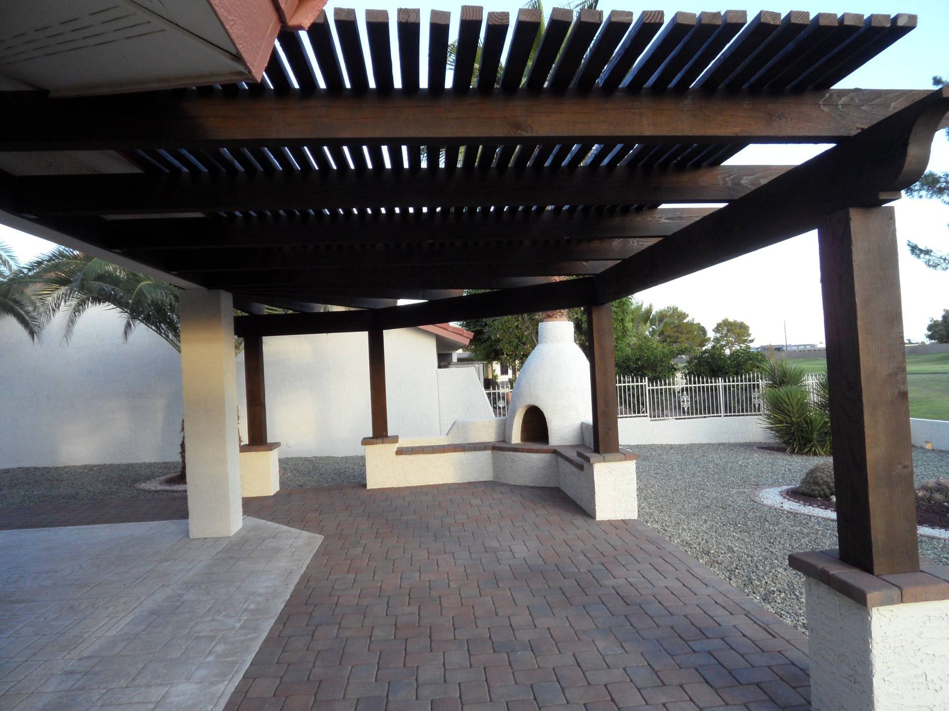 A wooden pergola with a fireplace underneath it