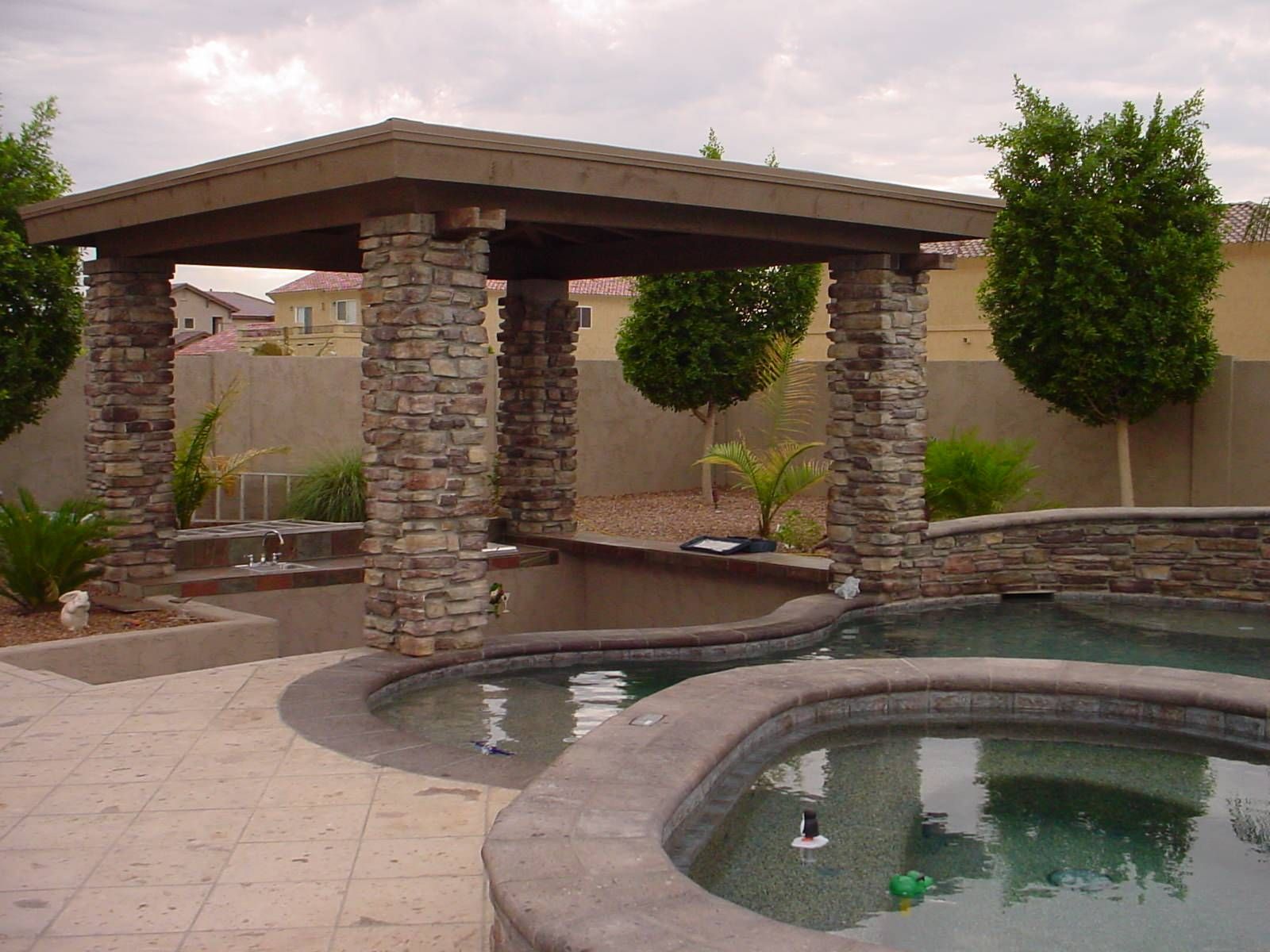 A gazebo over a swimming pool with trees in the background
