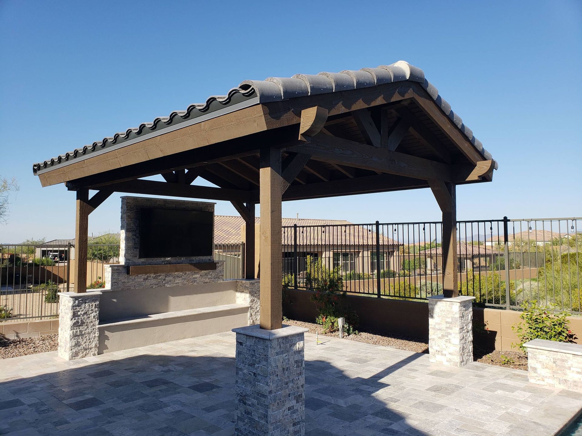 A wooden gazebo with a flat screen tv underneath it