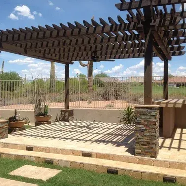 A wooden pergola is sitting on top of a patio.