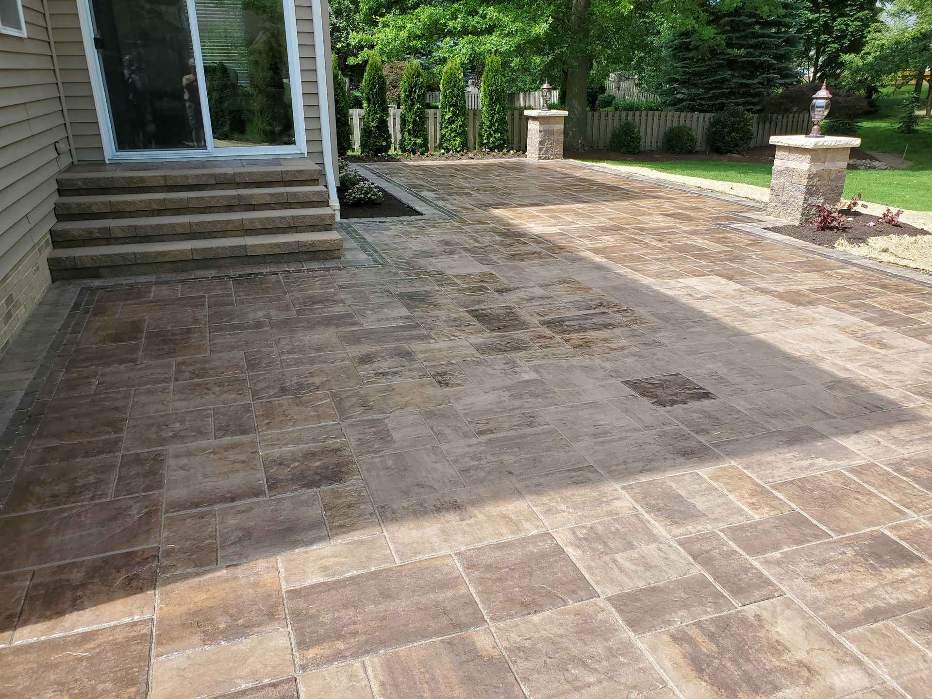 A patio with a sliding glass door and steps in front of a house.