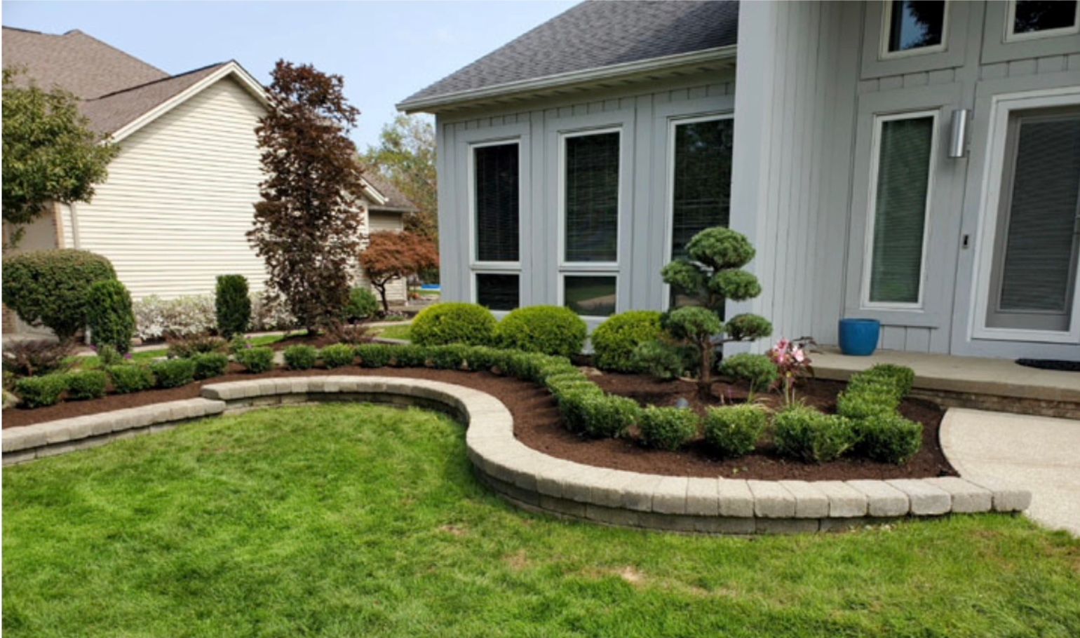 A house with a lush green lawn and a walkway in front of it.