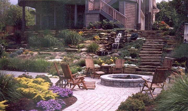 A patio with a fire pit and chairs in front of a house