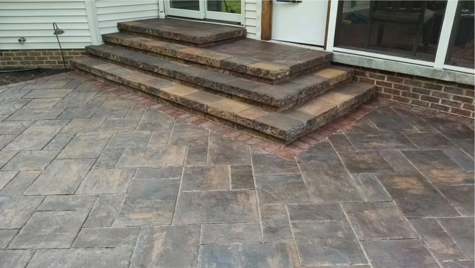 A patio with stairs leading up to a screened in porch.