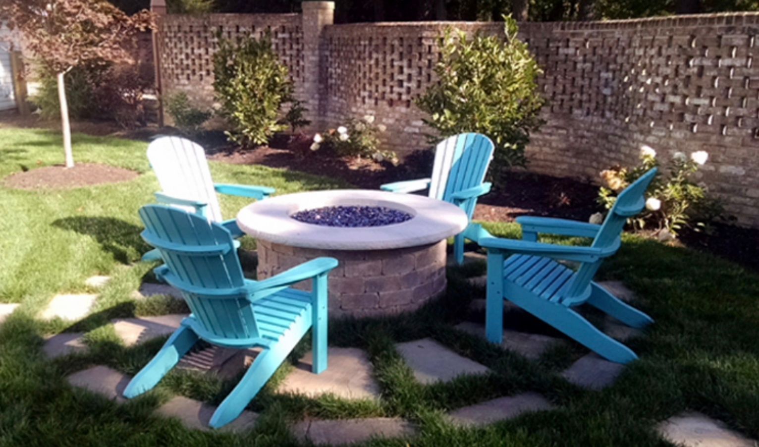 A fire pit surrounded by blue chairs in a backyard