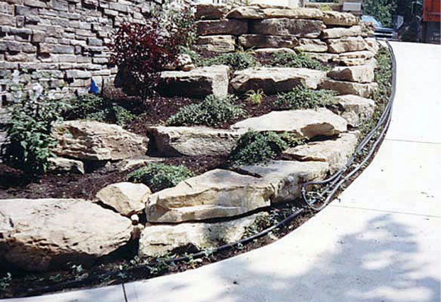 A rock garden with a brick wall in the background