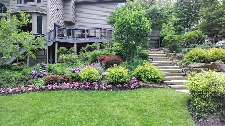 A large house with a lush green lawn and stairs leading up to it.