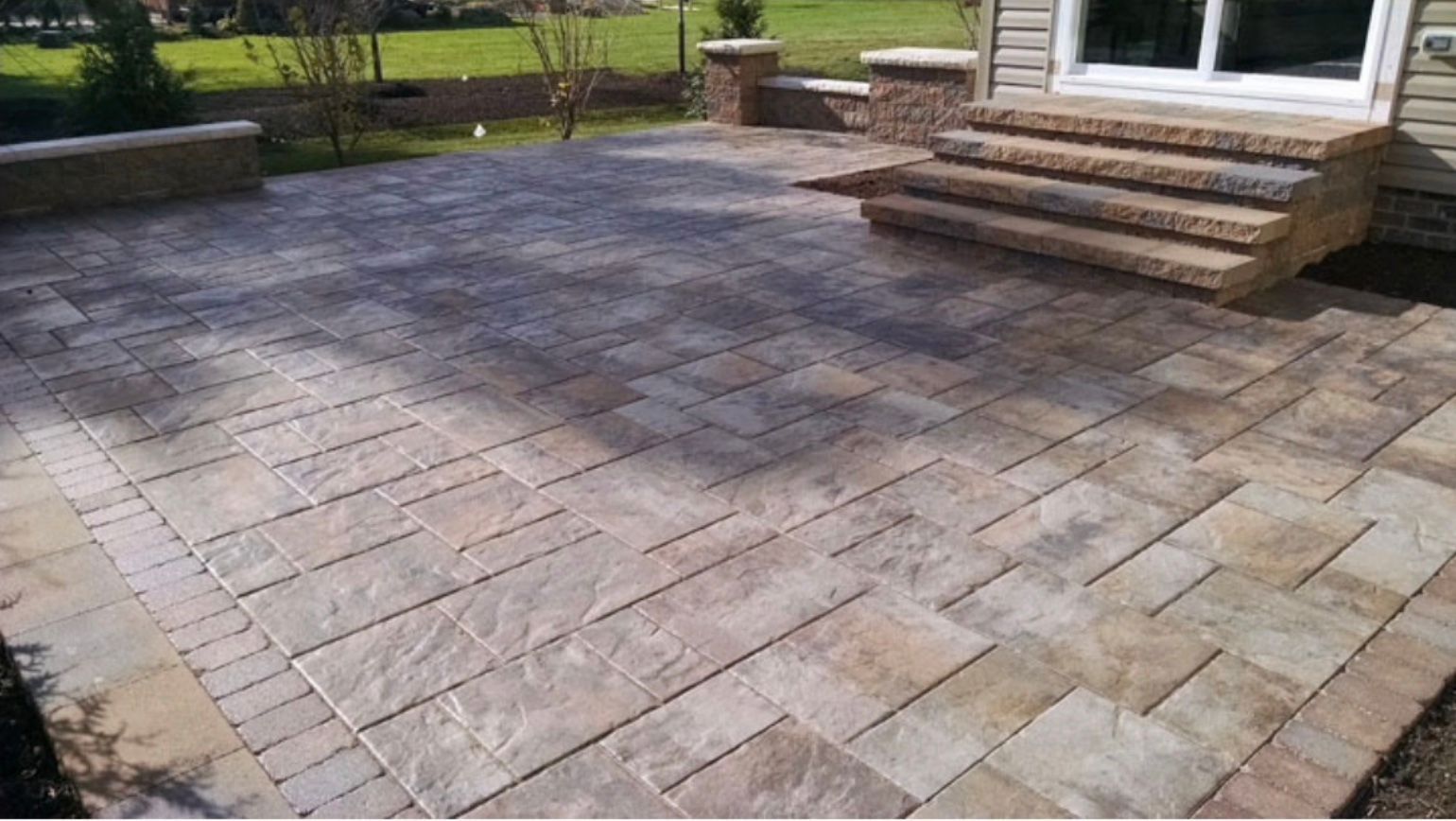 A patio with stairs leading up to it and a house in the background.