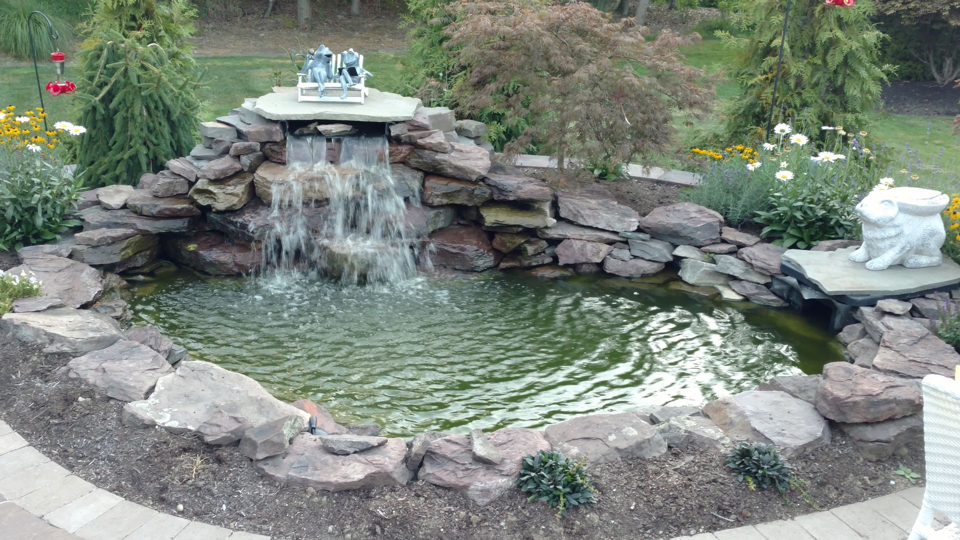 There is a waterfall in the middle of a pond surrounded by rocks.