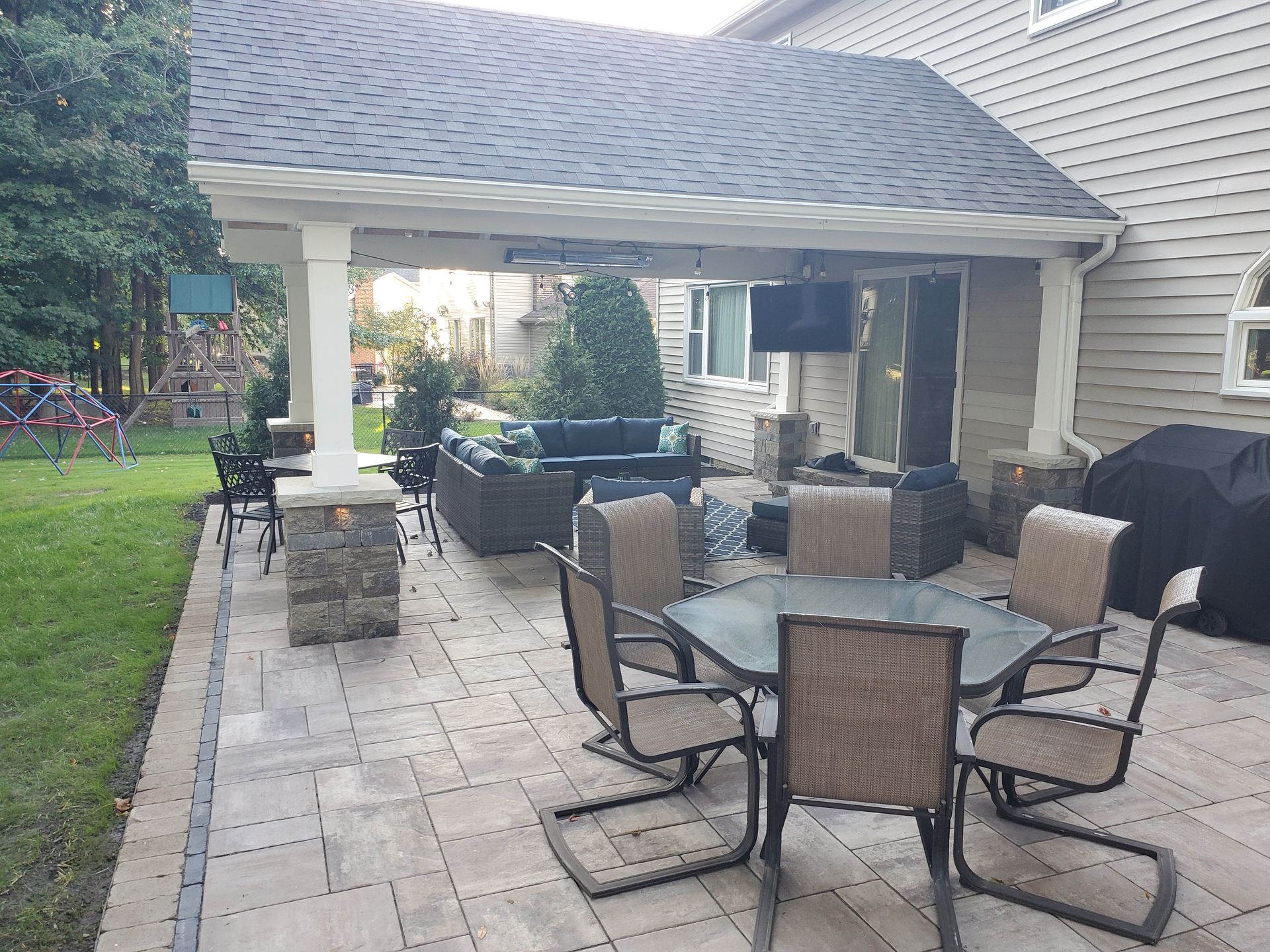 A patio with a table and chairs and a television on the roof.