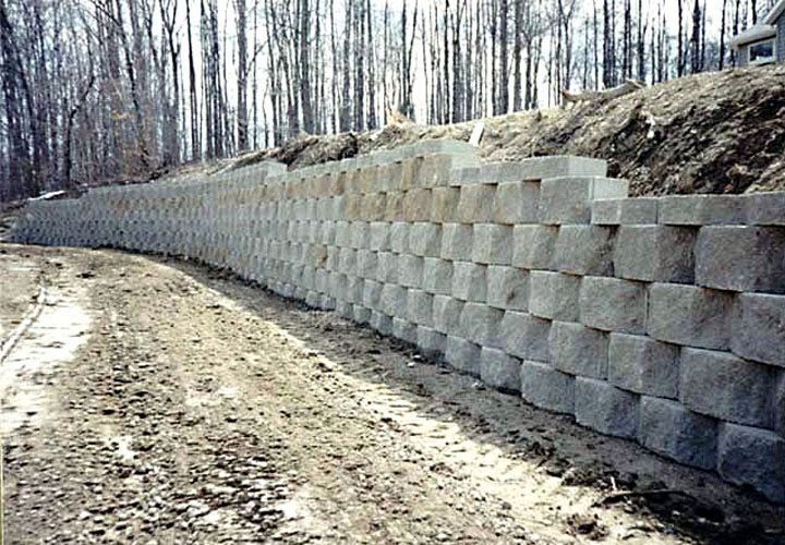 A large stone wall is along the side of a dirt road.