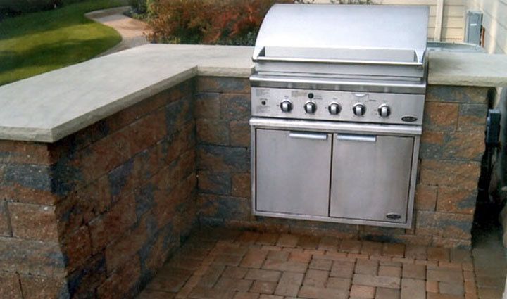 A stainless steel grill is mounted to a brick wall.